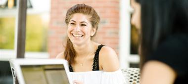 Woman outdoors sitting at a laptop computer and smiling