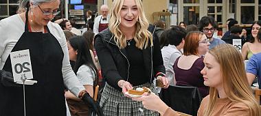 A student hands another a piece of pie.